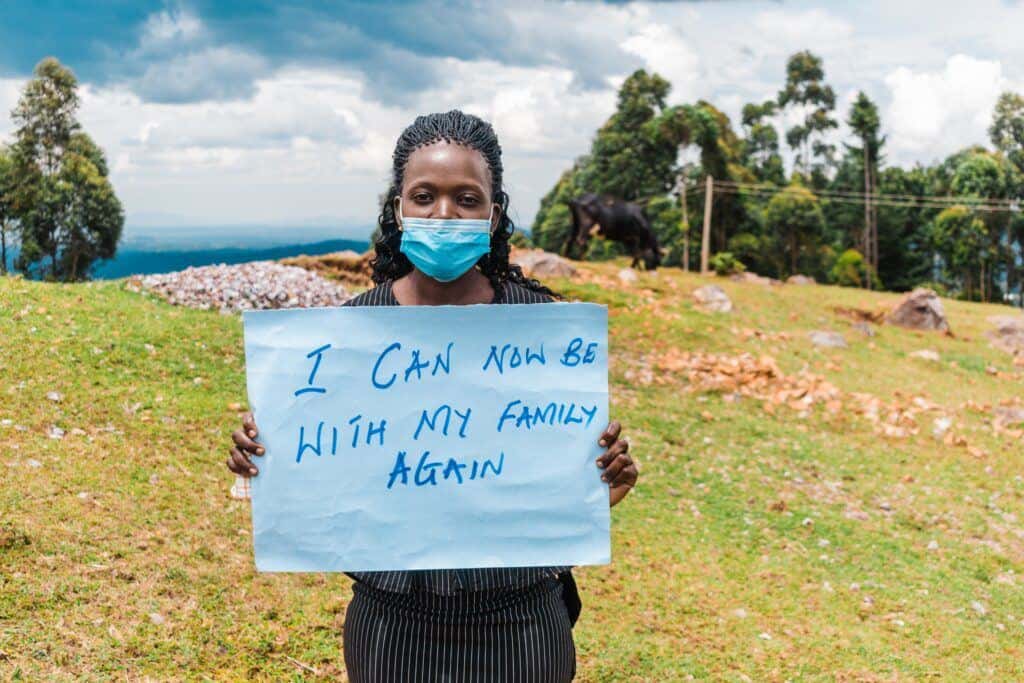 A fistula patient from Kenya holds up a sign that says, "I can now be with my family again."
